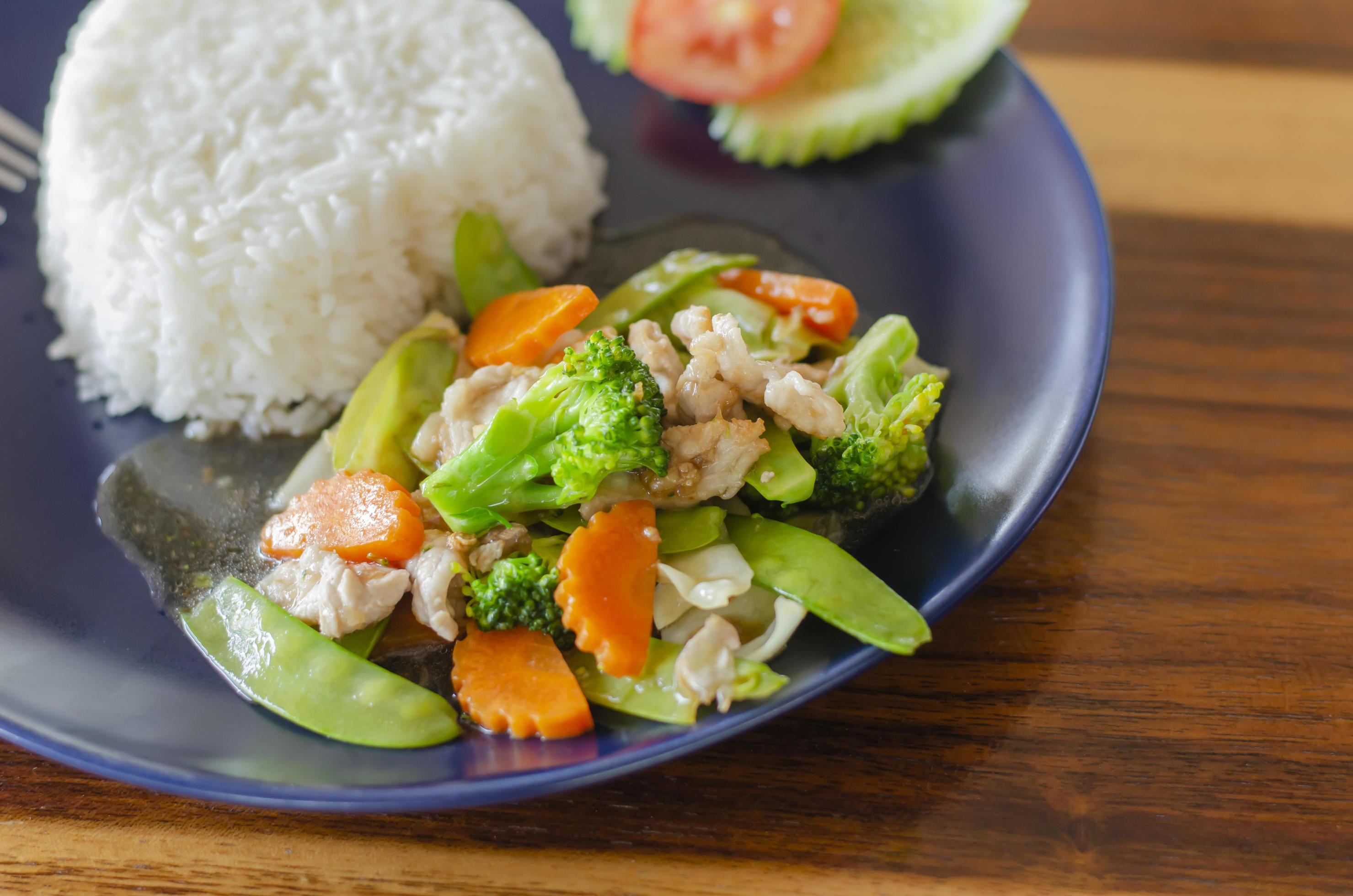 Stir fried mixed vegetables with pork or chicken tasty food, healthy food from Thailand Asia with wooden table background. side view Stock Free