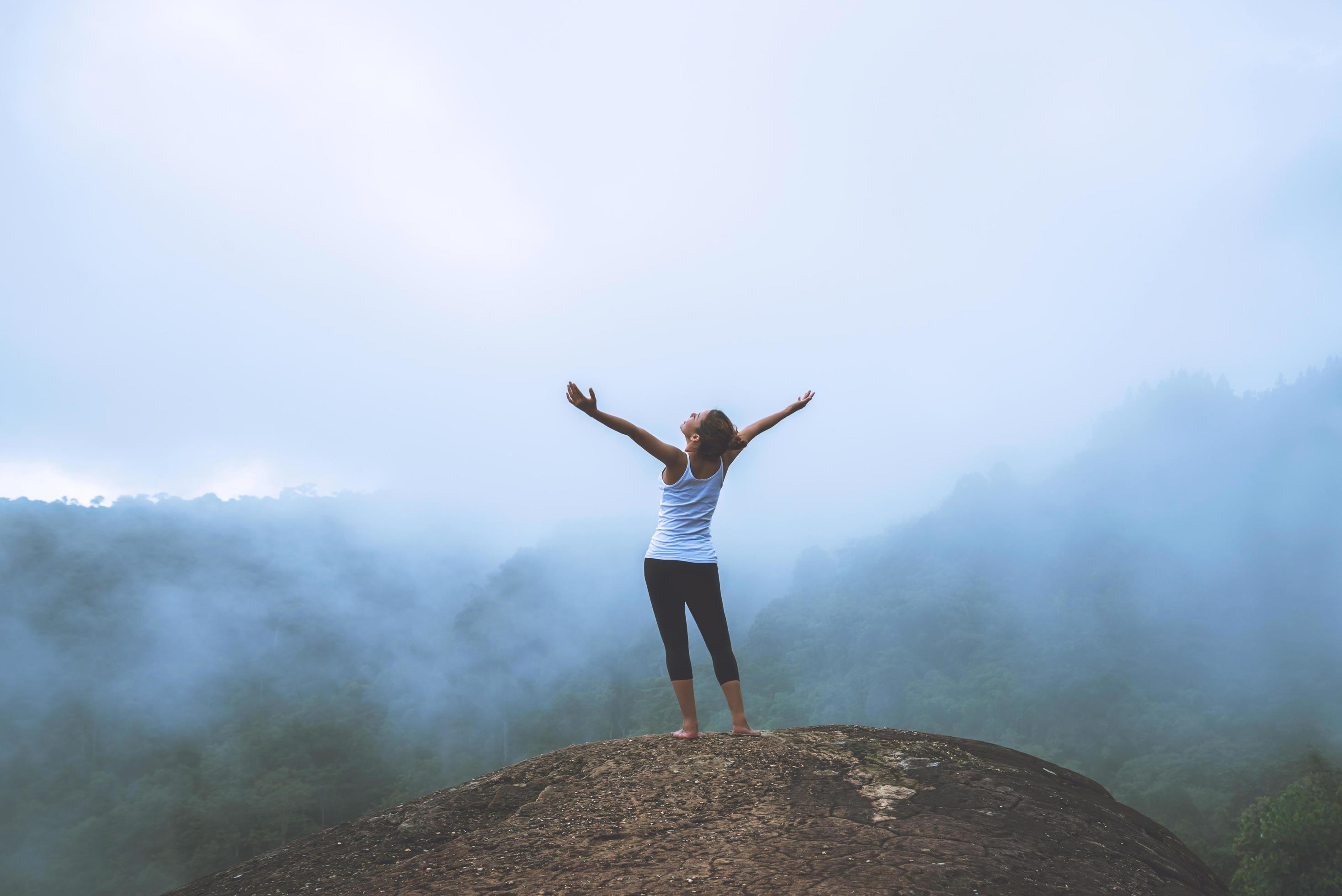 Young woman exercises yoga in the mountains. Asian woman travel nature. Travel relax exercises yoga touch natural fog on mountain peak. Stock Free