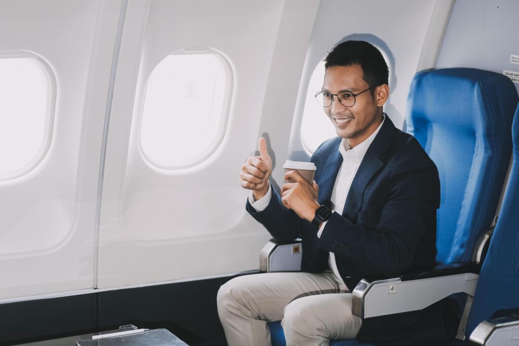 Satisfied businessman passenger drinking hot coffee while sitting on comfortable seat during business travel flight Stock Free