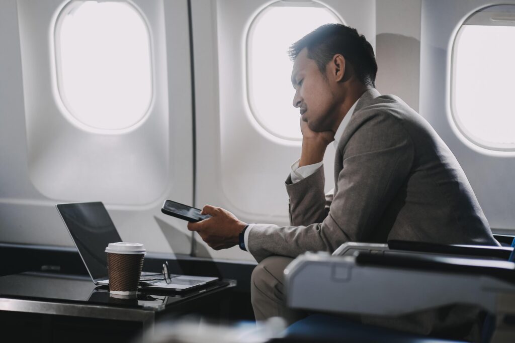 Stressed and professional Asian businessman in a business class, having a serious phone call with someone during the flight to a business meeting. Stock Free