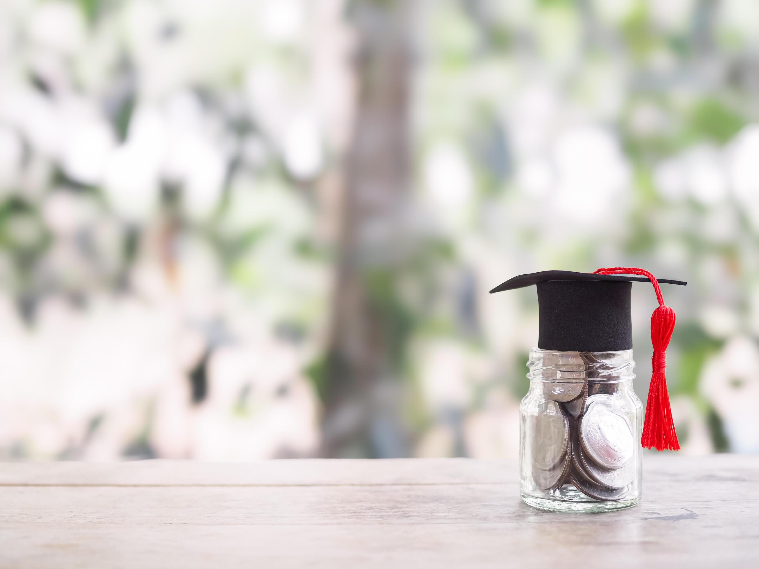 Glass bottle with graduation hat. The concept of saving money for education, student loan, scholarship, tuition fees in the future Stock Free