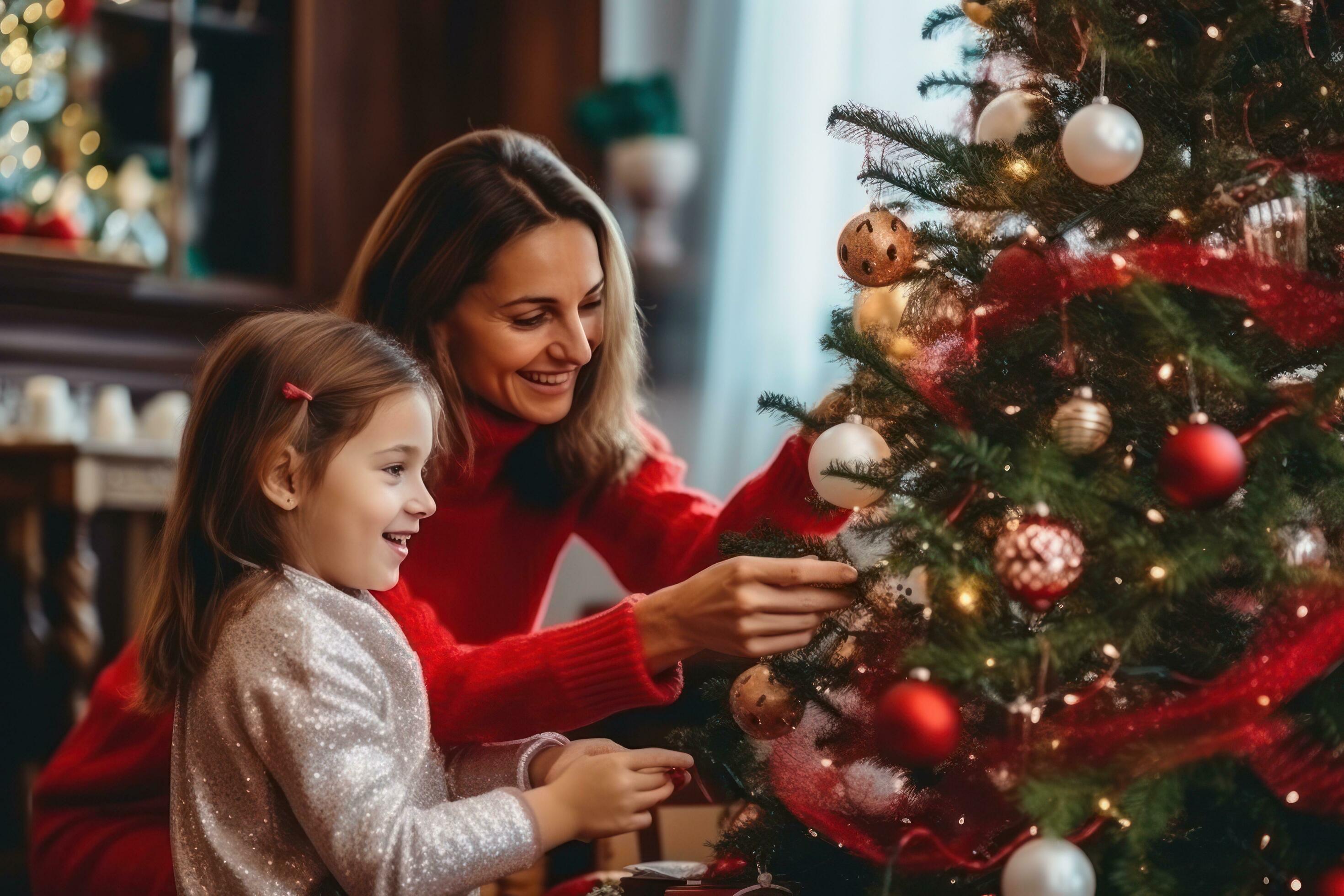 Woman and girl decorate christmas tree with toys Stock Free