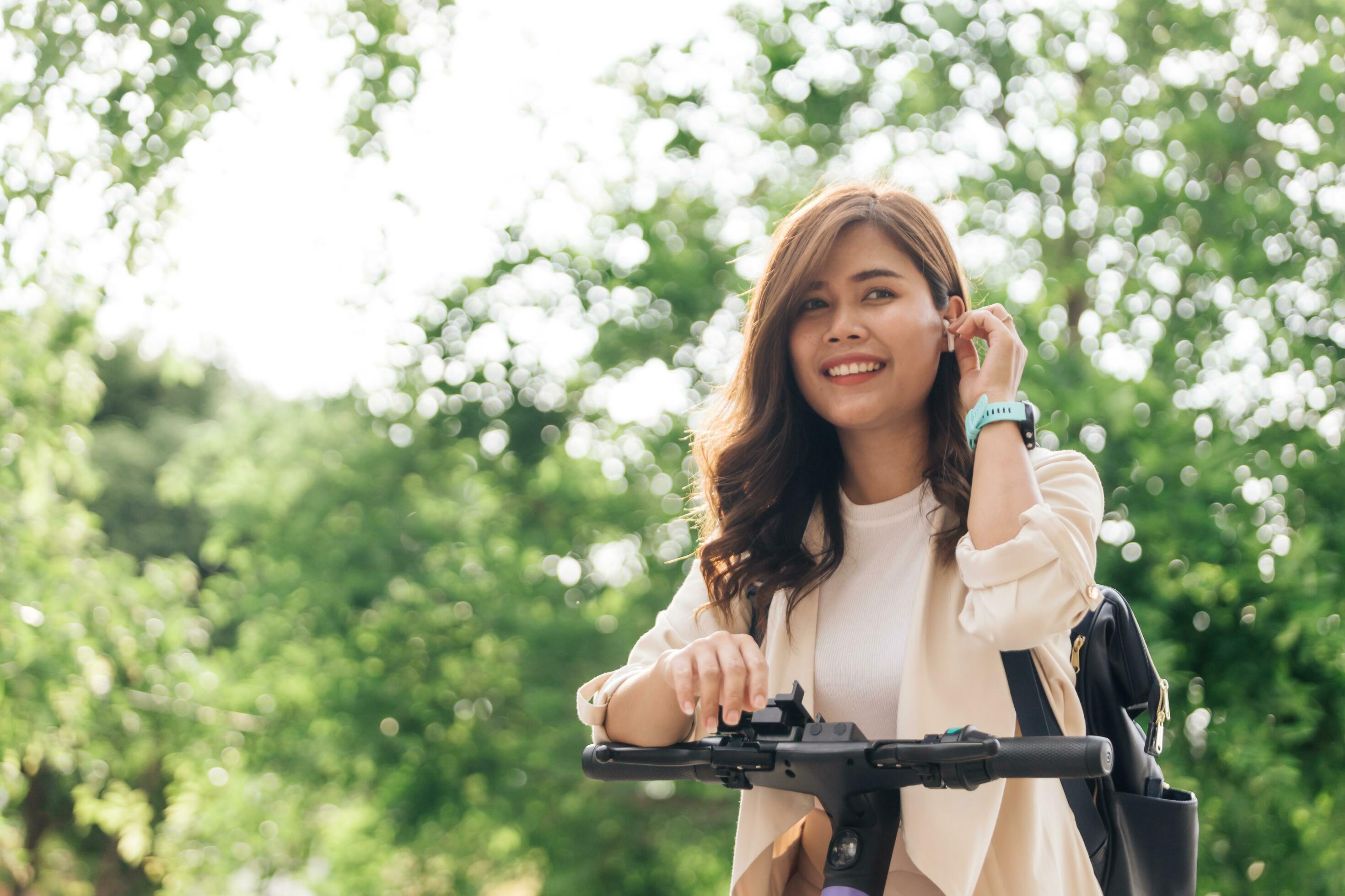 Young asian woman riding a scooter in the park. Healthy lifestyle concept. Stock Free