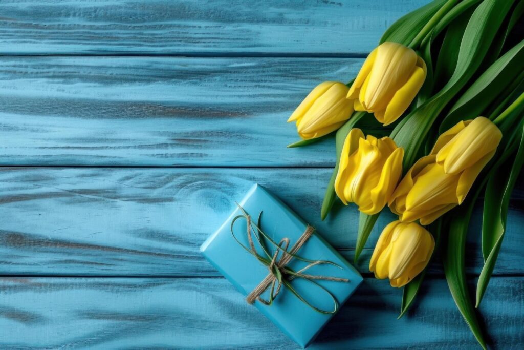 yellow tulips with blue gift box on blue wooden background Free Photo