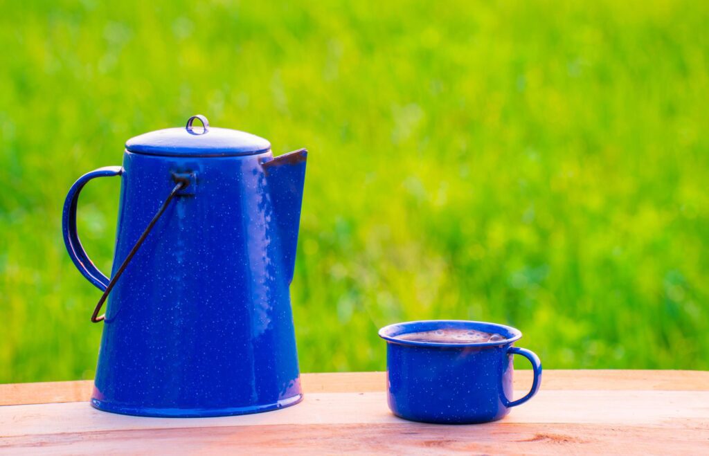 Kettle, blue enamel, and coffee mugs On an old wooden floor, Blurred background of rice fields at sunrise. Stock Free