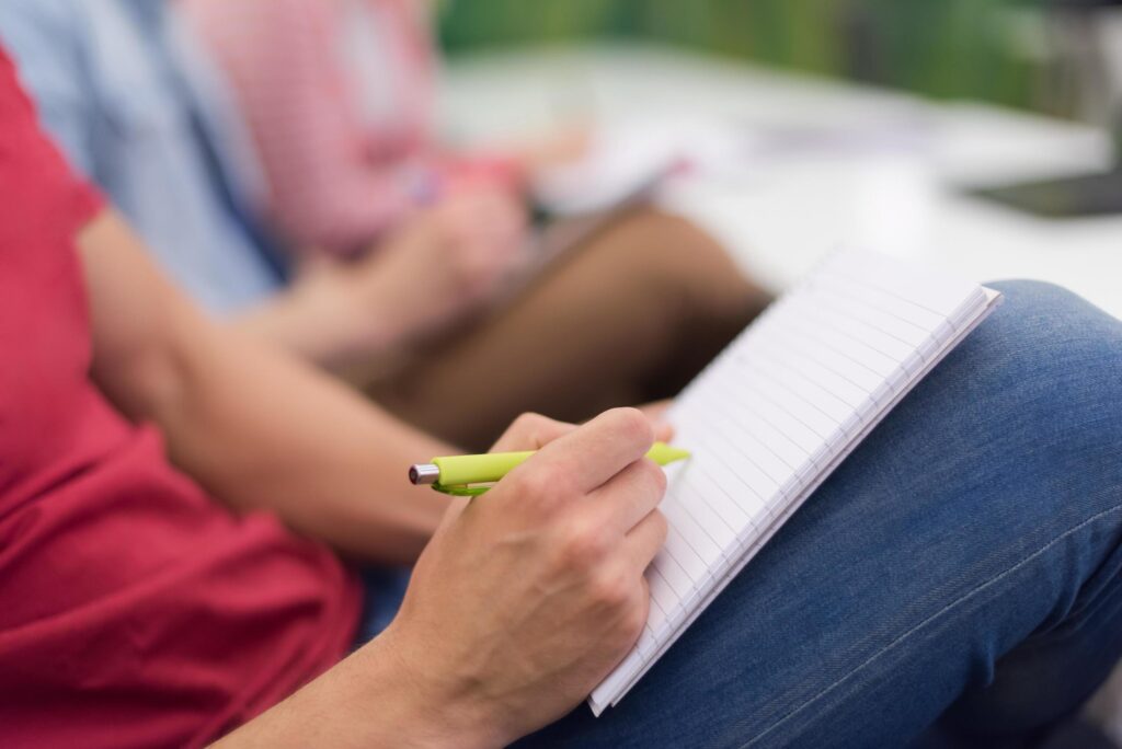 male student taking notes in classroom Stock Free