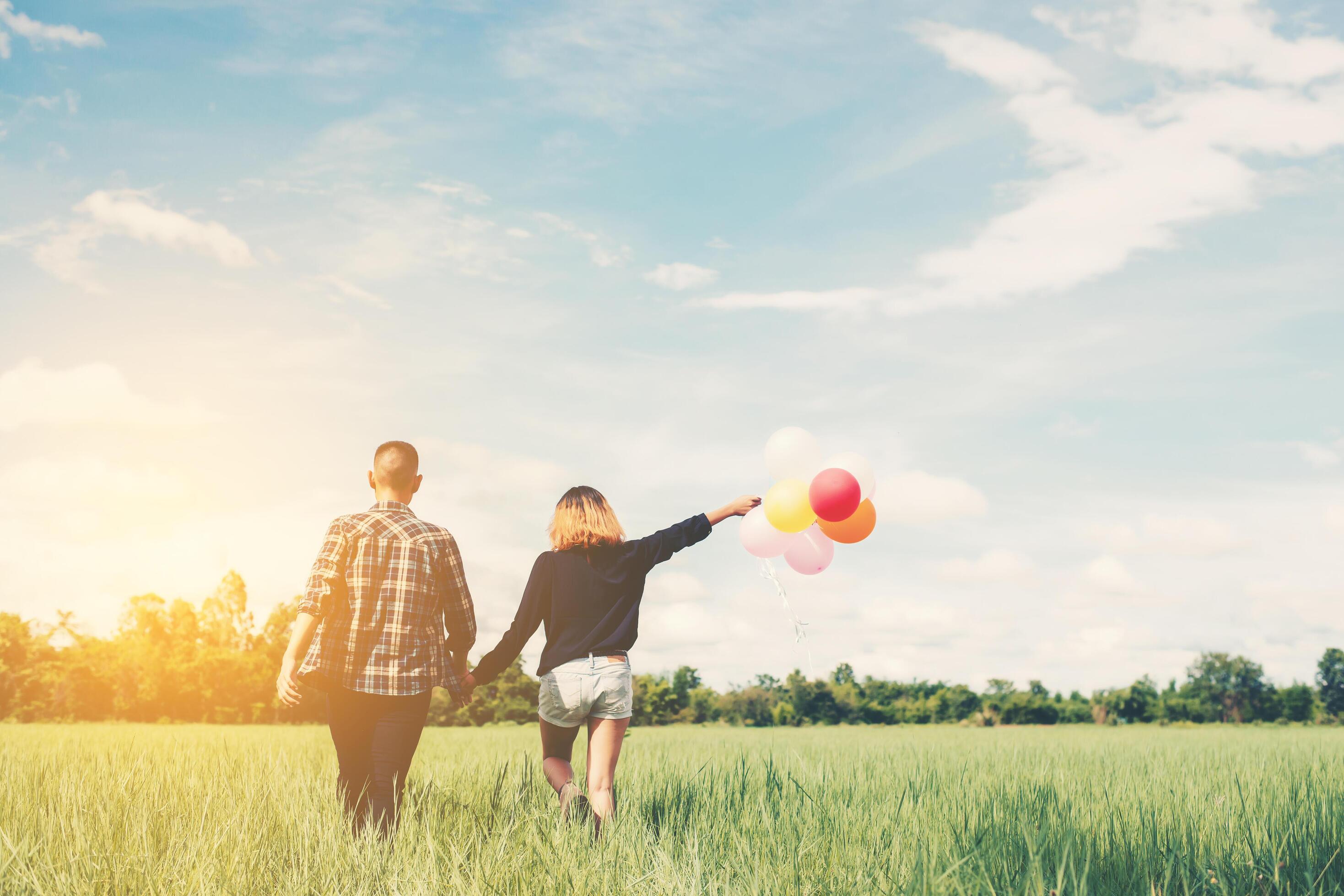 Back of happy young asian couple holding balloon and walk together. Stock Free