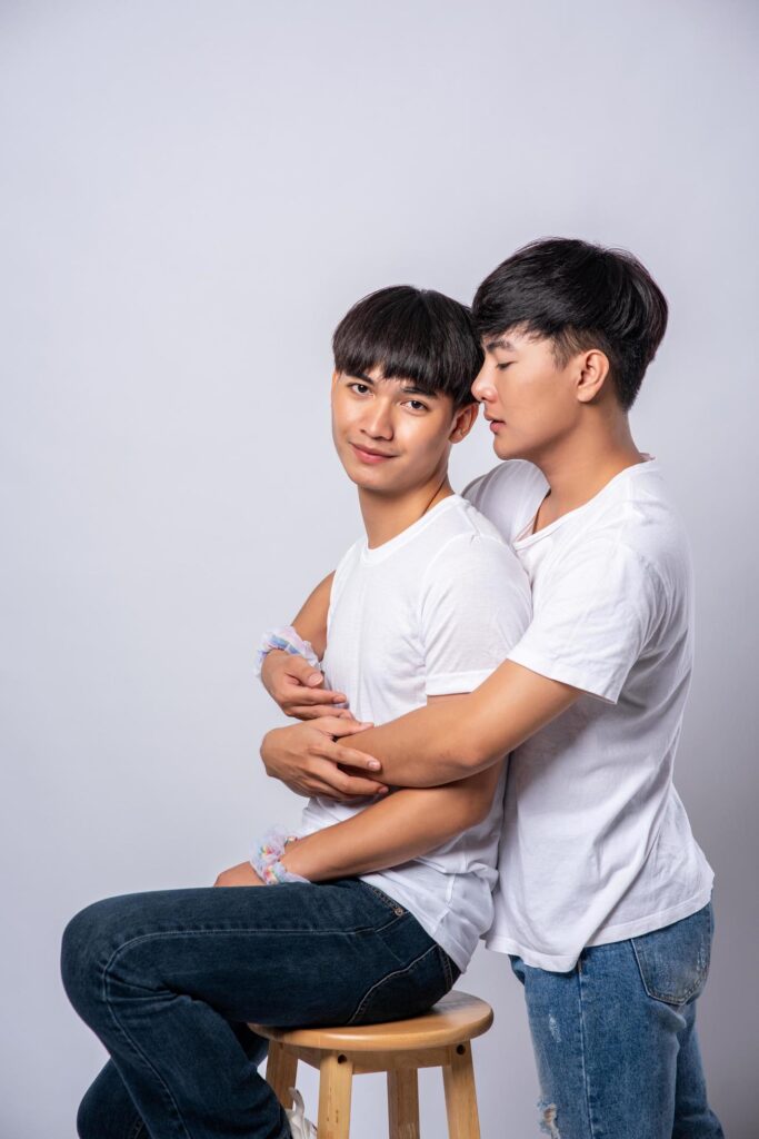 Two men who love each other hug and sit on a chair. Free Photo