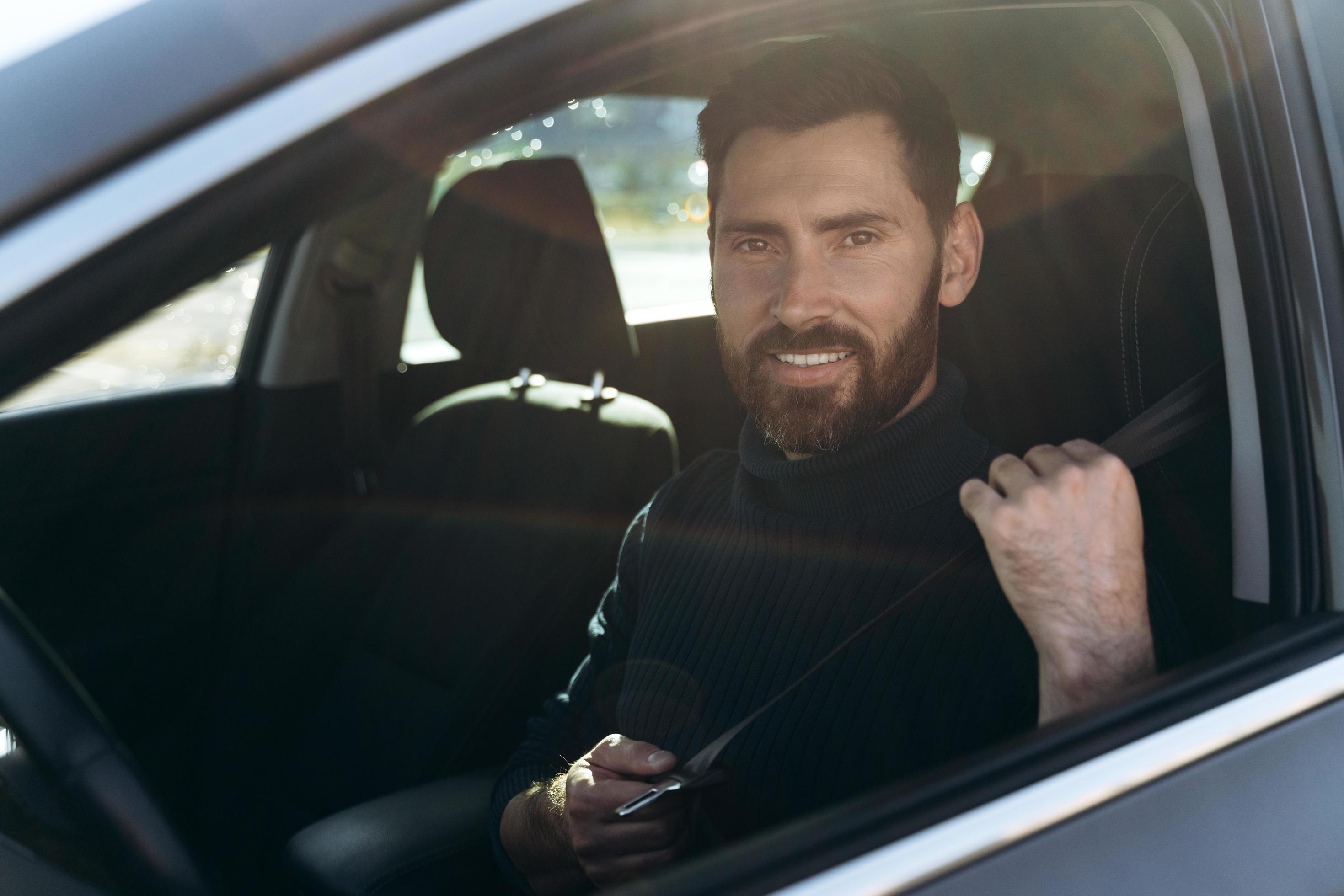 Happy caucasian man sitting and looking at the window while having long road by the car. Busy people and transportation concept Stock Free