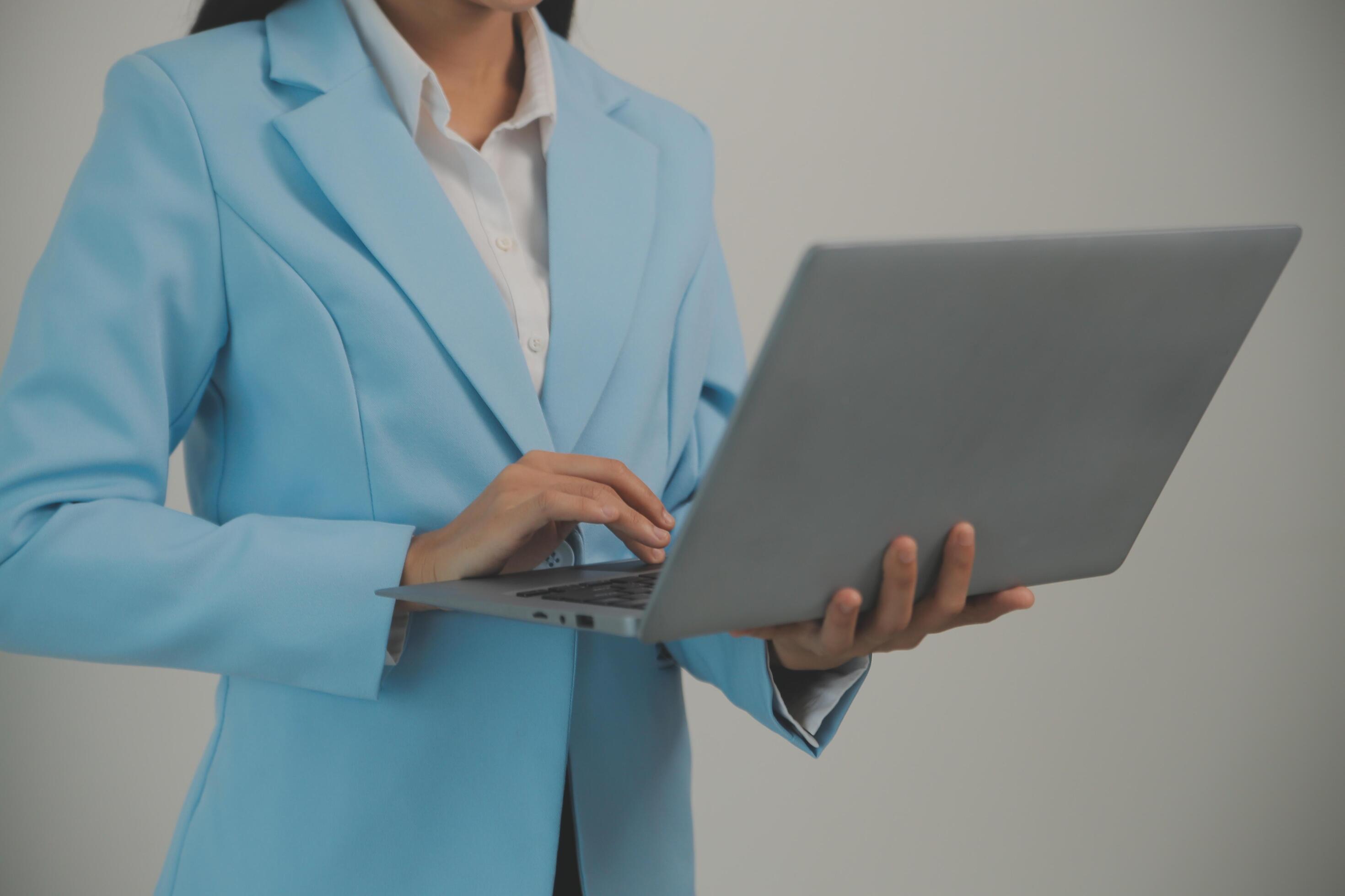 Portrait of a happy asian businesswoman working on laptop computer isolated over white background Stock Free