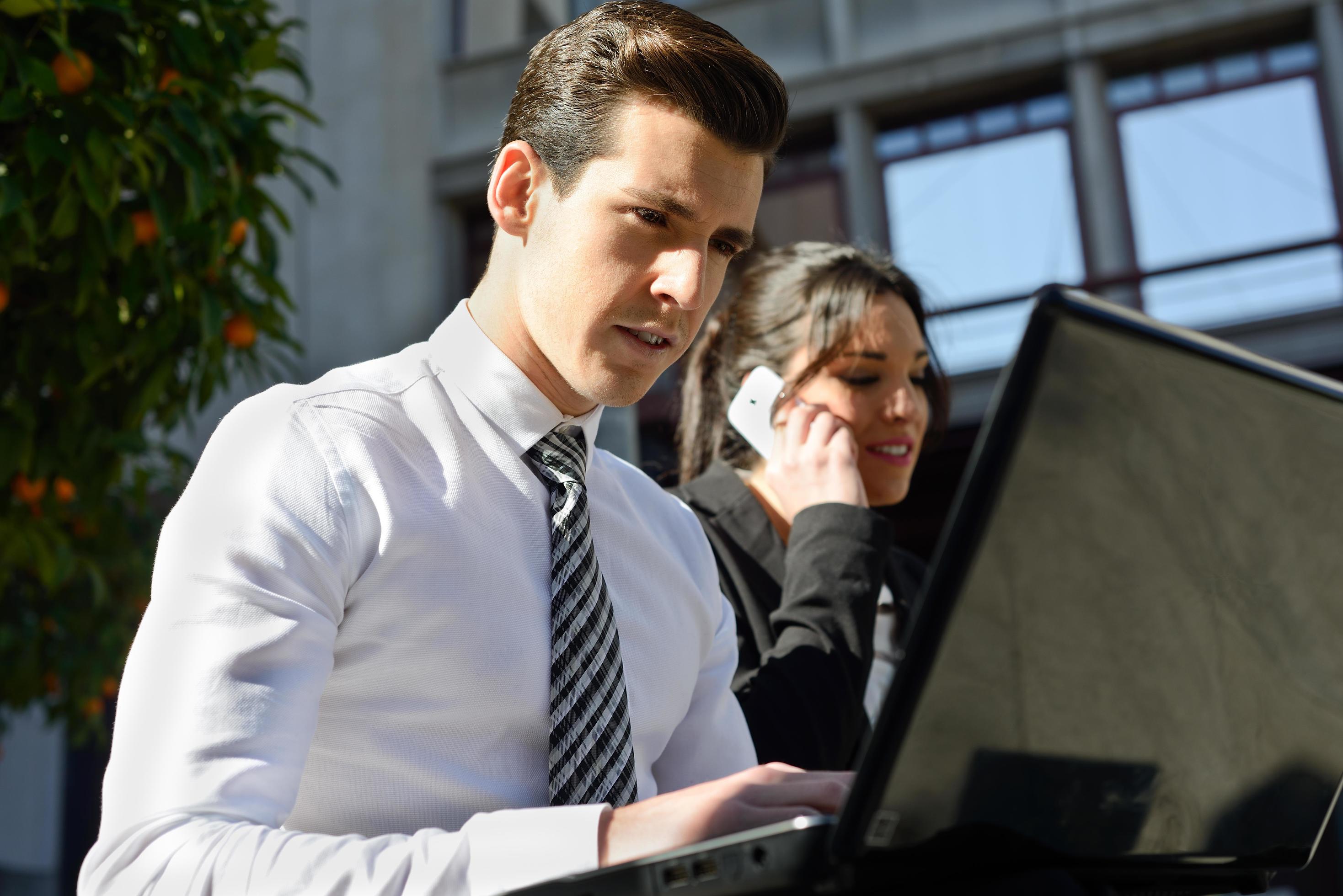 Young businessman typing in a laptop computer in urban background Stock Free