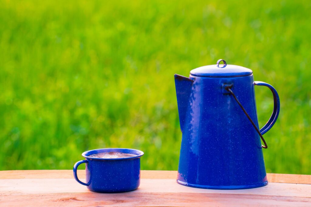 Kettle, blue enamel, and coffee mugs On an old wooden floor, Blurred background of rice fields at sunrise. Stock Free