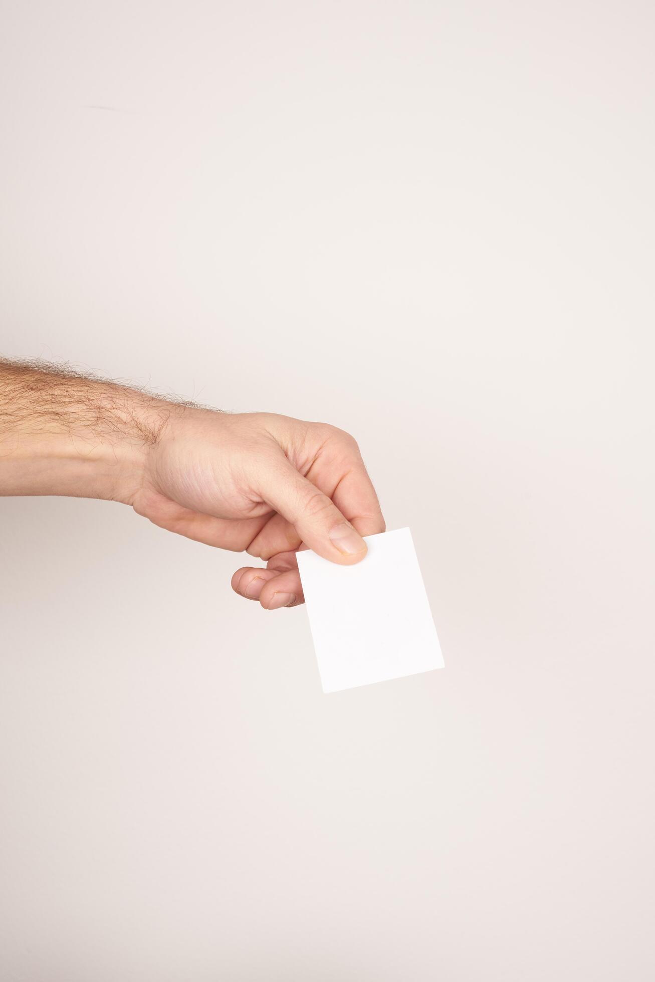 Male hand holding and giving a white blank business card Stock Free