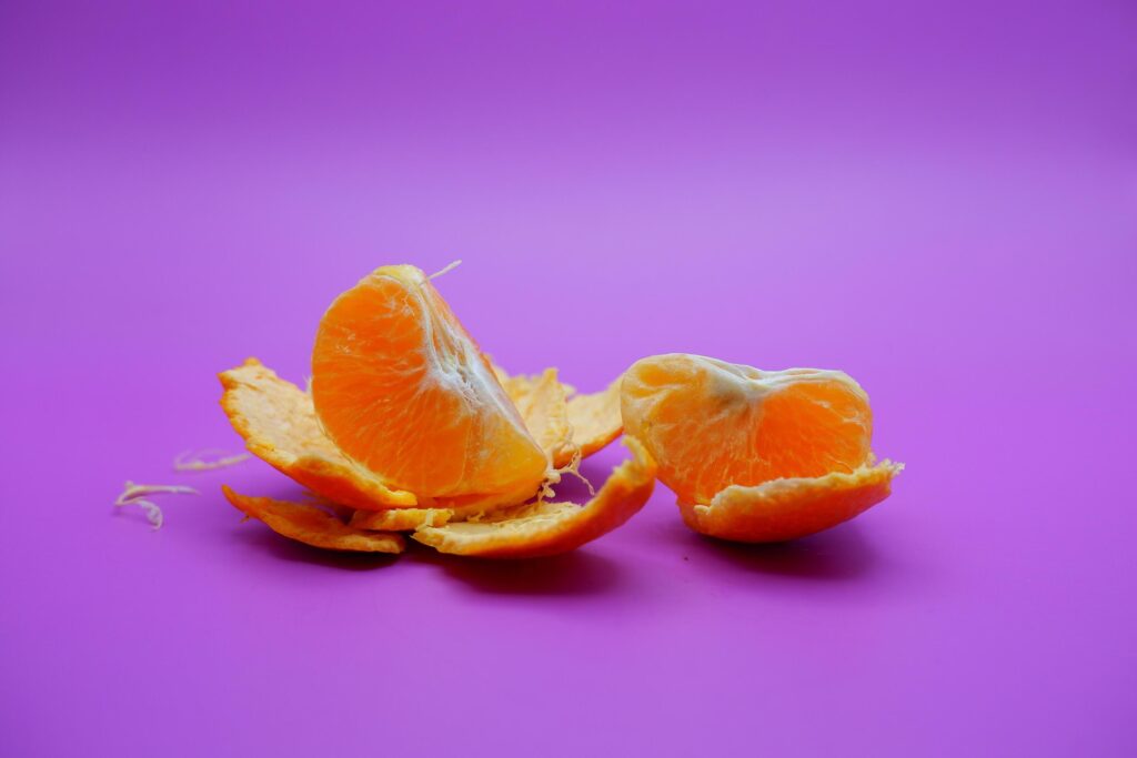 orange and peel isolated on purple background Stock Free