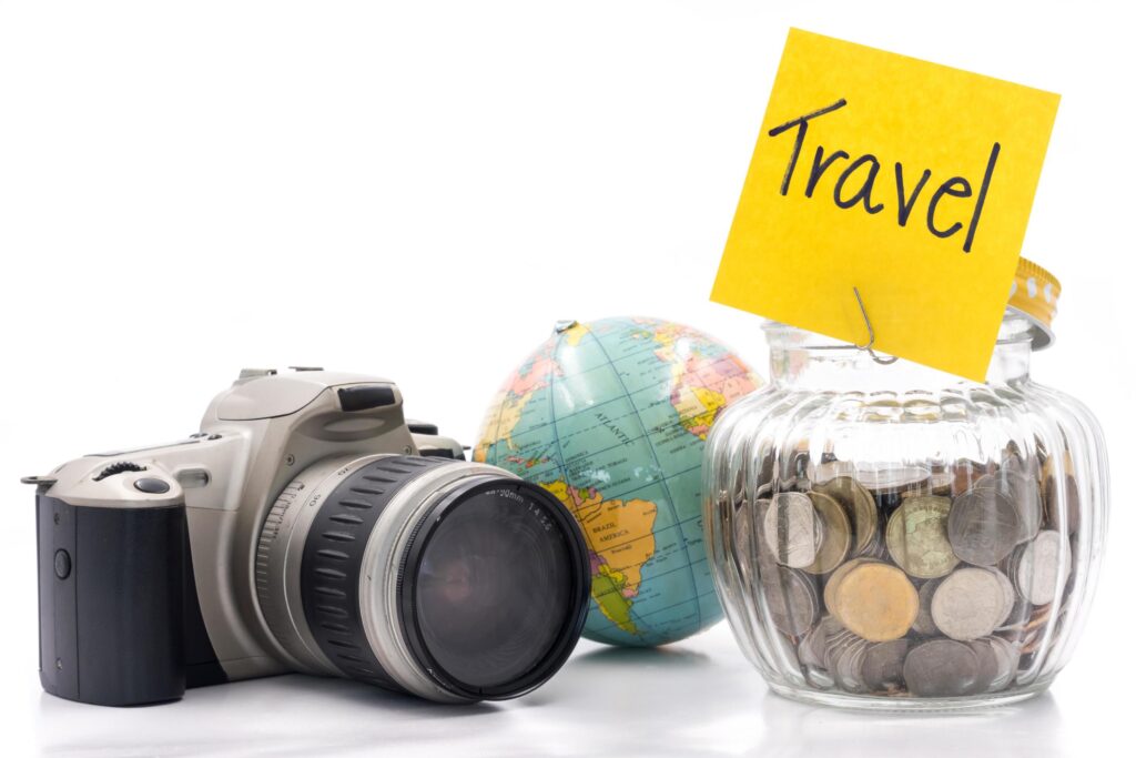 Coins in glass bottle with camera and globe on white background, saving money for Travel Stock Free