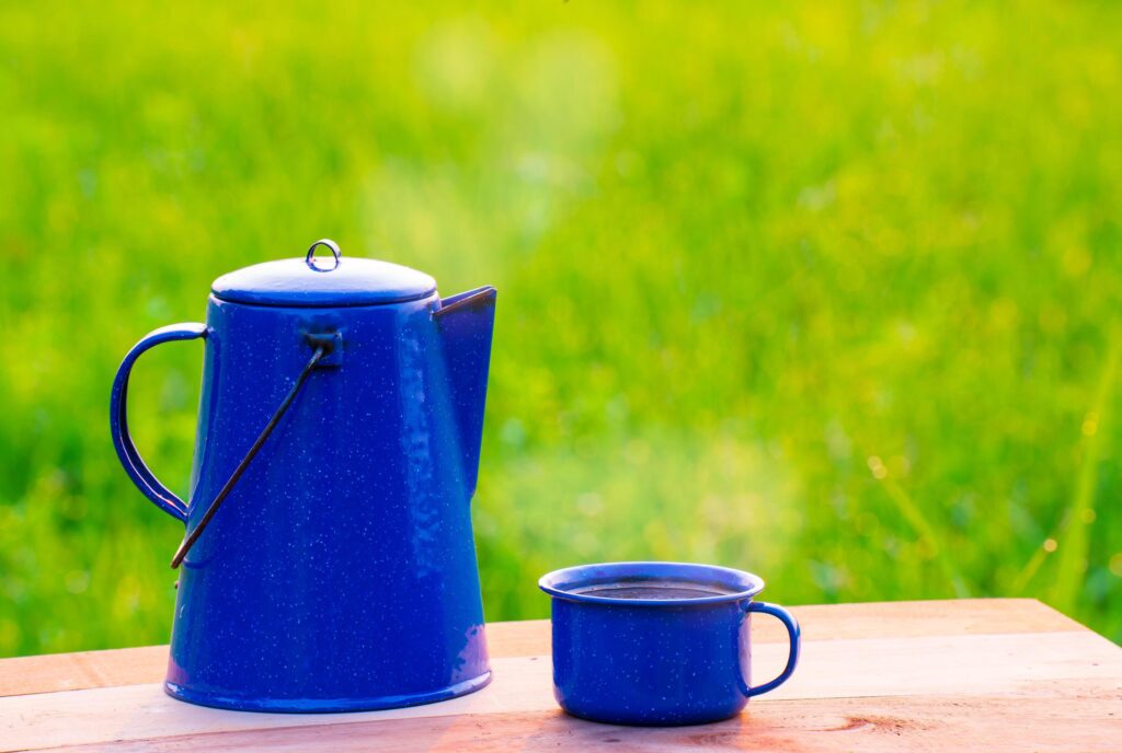 Kettle, blue enamel, and coffee mugs On an old wooden floor, Blurred background of rice fields at sunrise. Stock Free