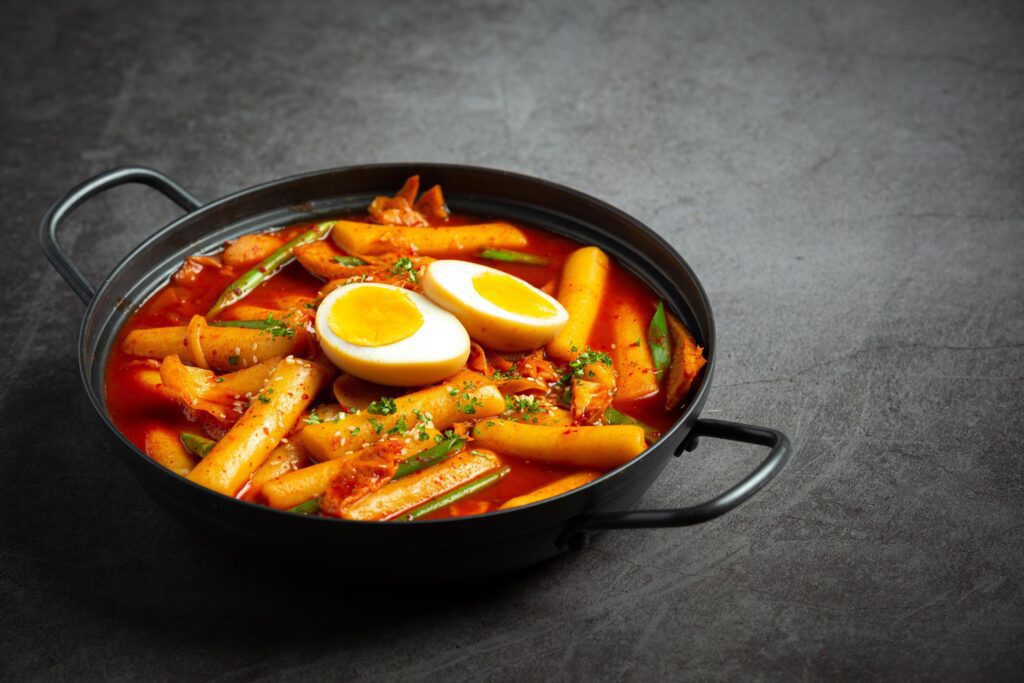 Cheesy Tokbokki korean traditional food on black board background. Lunch dish. Stock Free