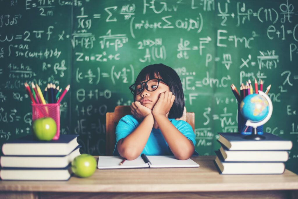 Thoughtful little girl with book near a school board Stock Free