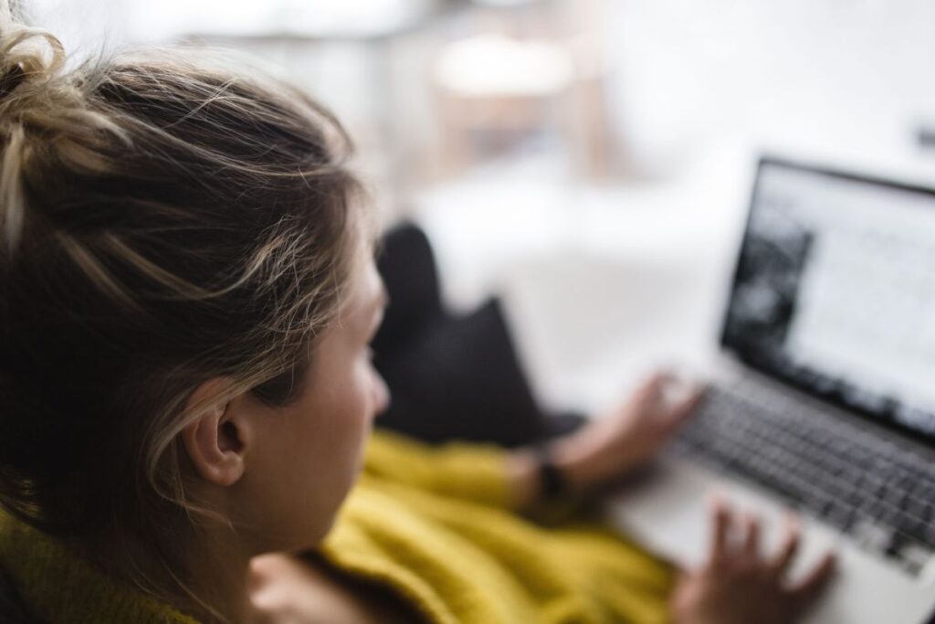 Young woman sitting on the sofa and working on her laptop Stock Free