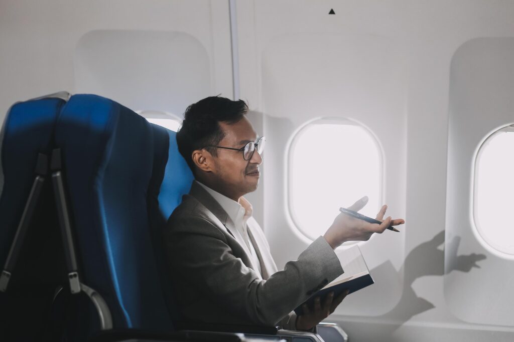 Airplane, travel and portrait of businessman working on laptop computer and smartphone while sitting in airplane. Stock Free