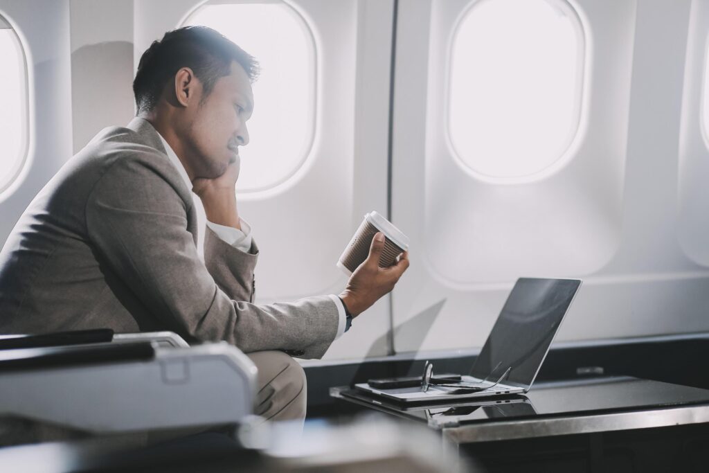 Stressed and professional Asian businessman in a business class, having a serious phone call with someone during the flight to a business meeting. Stock Free