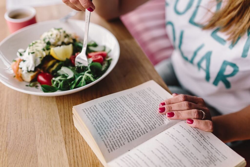 
									Woman eating breakfast and reading a book Stock Free