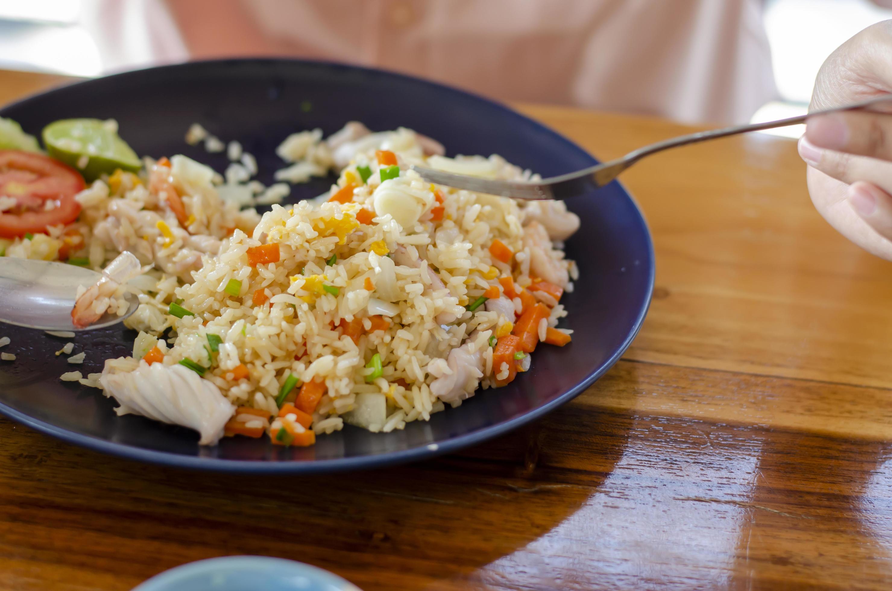 seafood fried rice, asian woman eating, popular thai food Stock Free