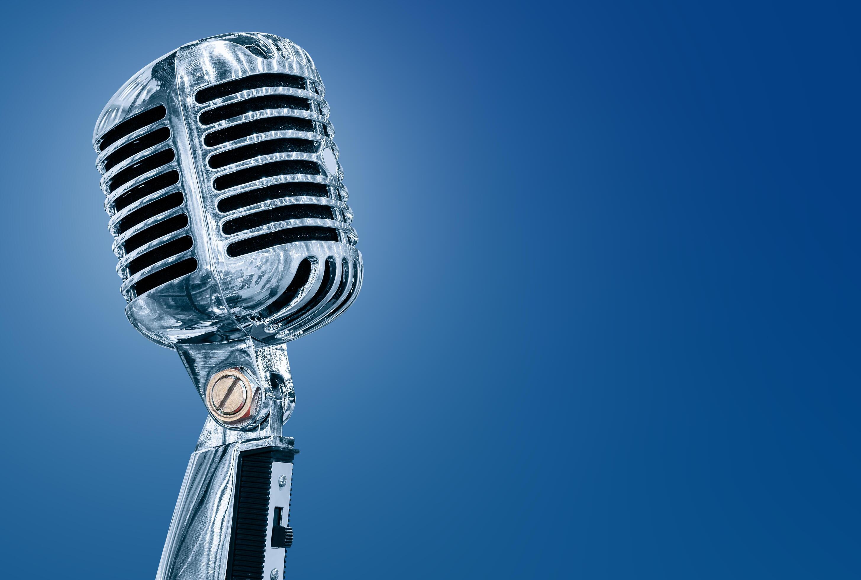 Silver retro microphone isolated on blue background Stock Free