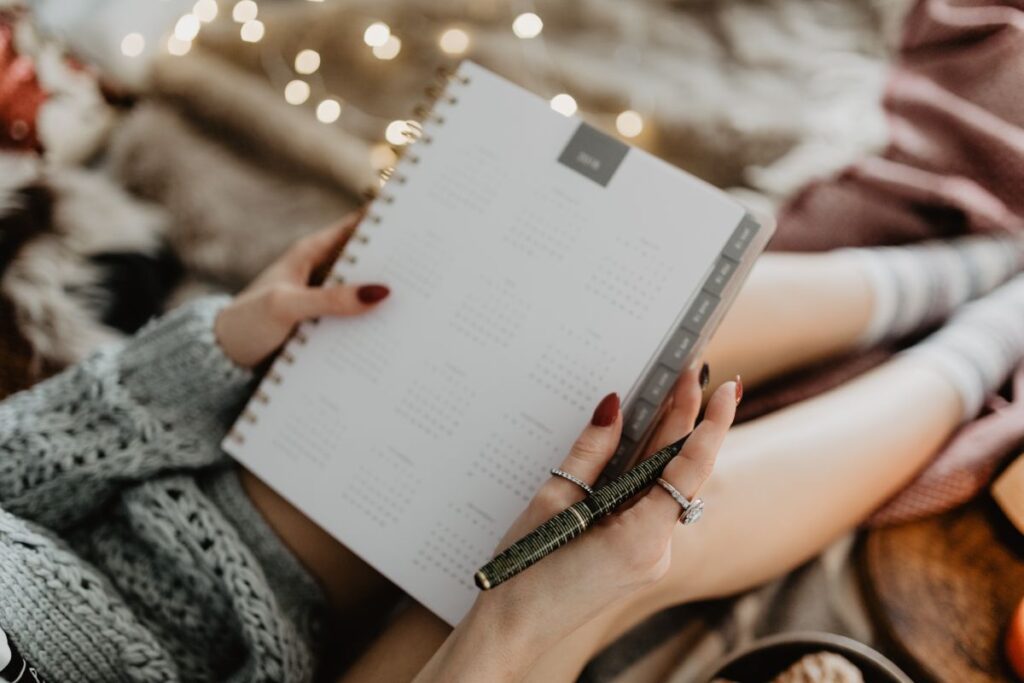 Writing in a notebook lying in bed, with coffee, candles, and gingerbreads Stock Free