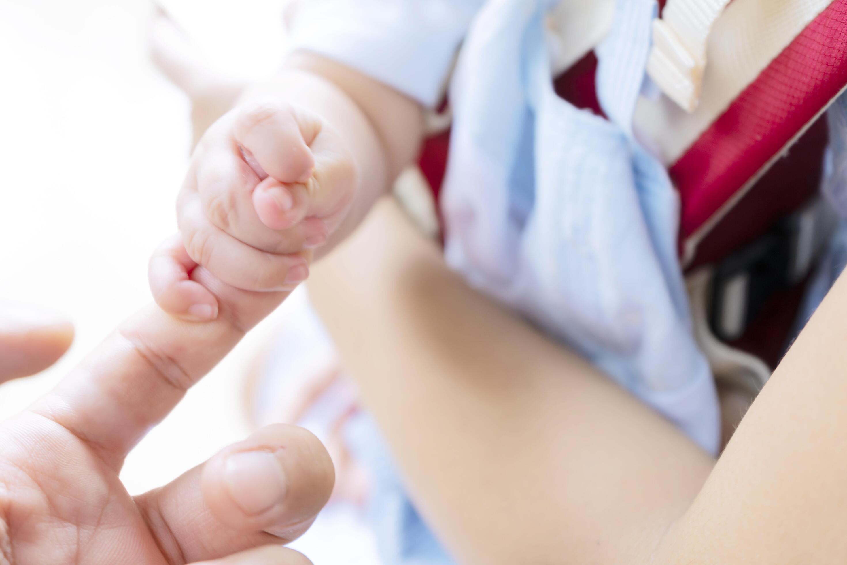 concept of love and family. hands of mother and baby closeup. A child who is in his mother’s embrace and is holding his father’s fingers. Stock Free