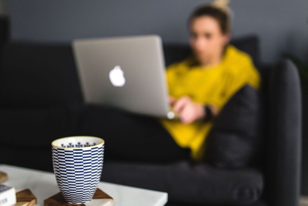 Young woman sitting on the sofa and working on her laptop Stock Free