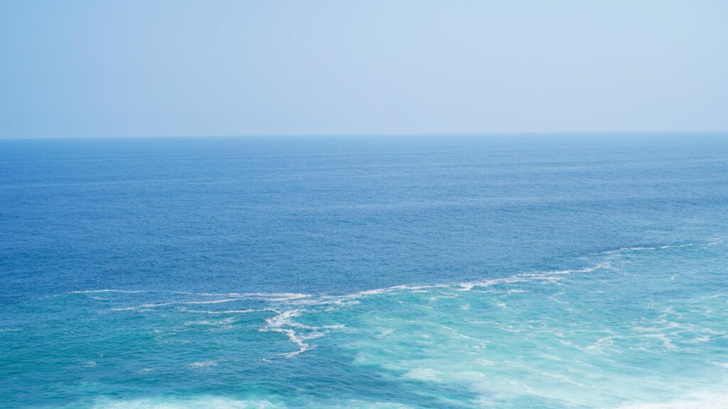 Front view over the ocean and white foam waves. Feel calm, cool, relaxed. Idea for cool background and copy space above. Stock Free