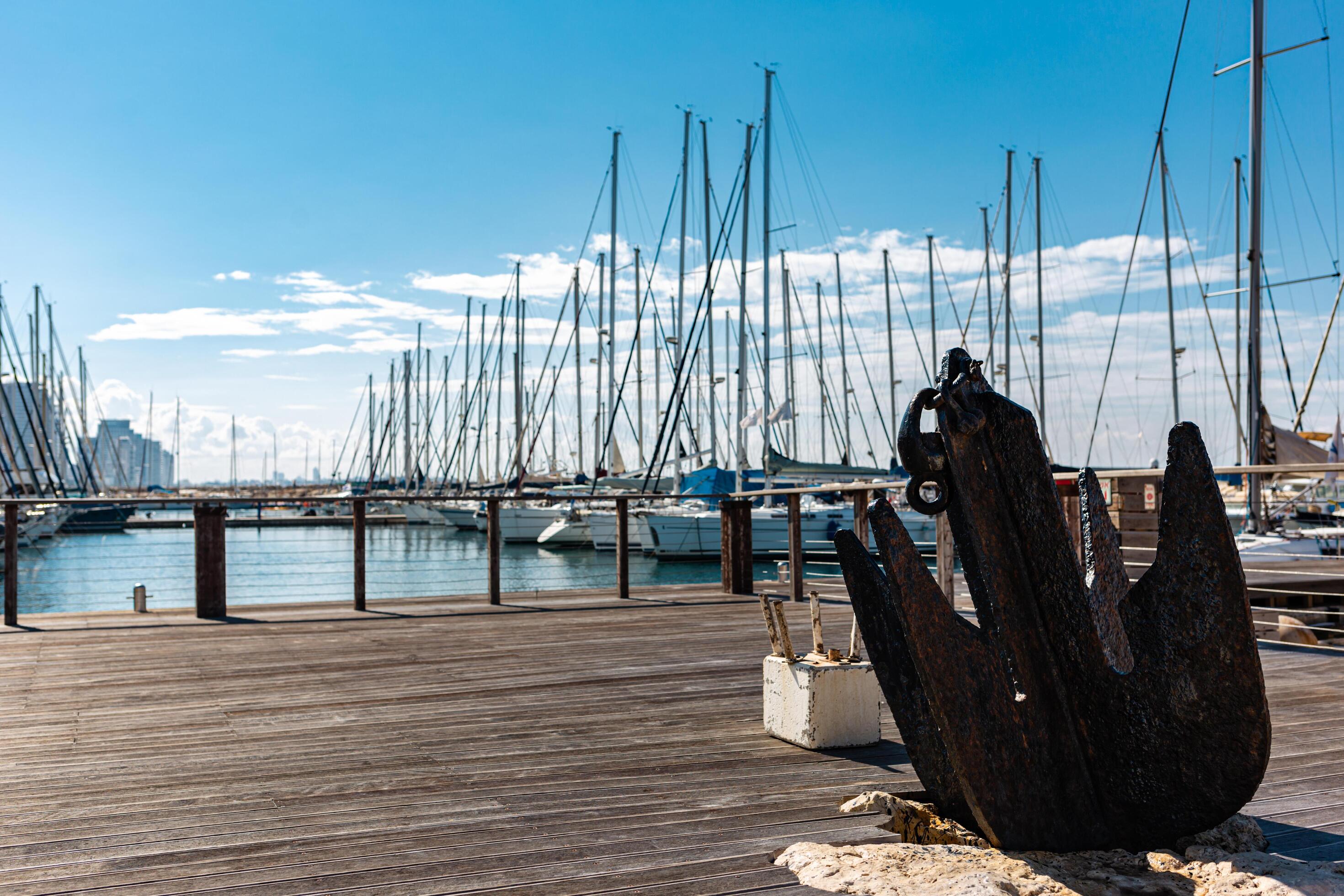 Old anchor on embankment near Marina. Bright blue sky and skyscapers on background. Tel Aviv city, Israel. Stock Free