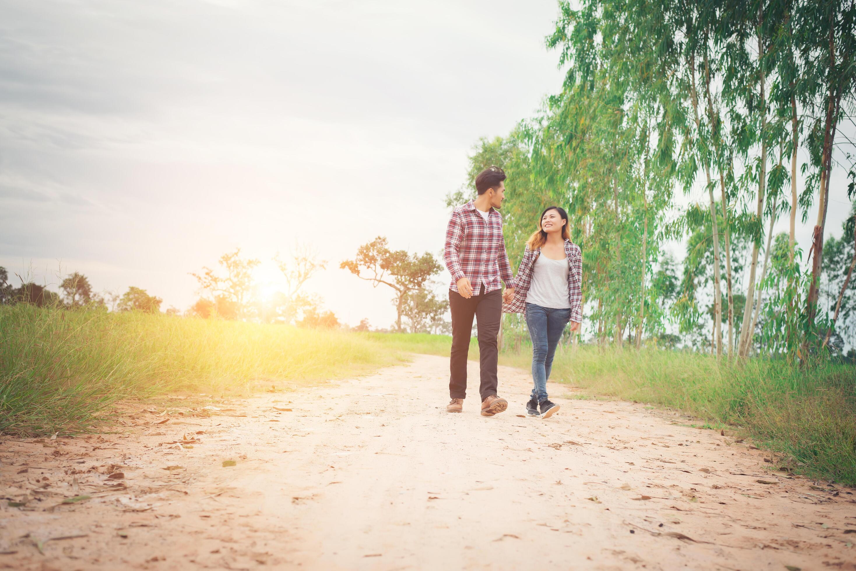 Young hipster couple walking on rural road enjoying with nature, Love couple,holiday traveling, spend time together. Stock Free