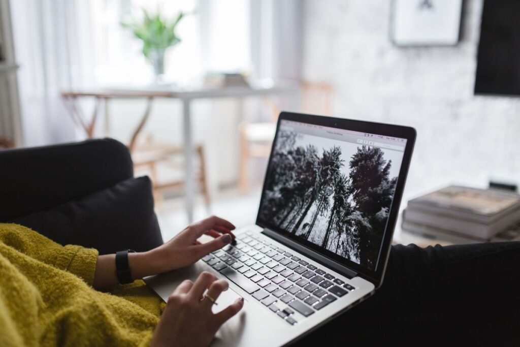 Young woman sitting on the sofa and working on her laptop Stock Free