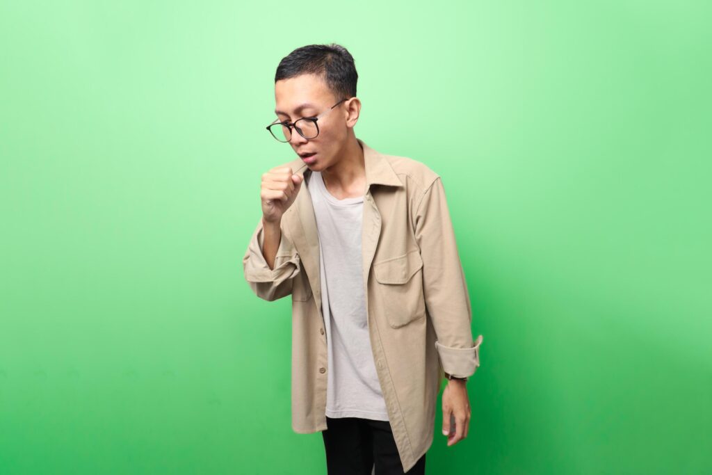 man in tan jacket having cough or influenza isolated on green background Stock Free