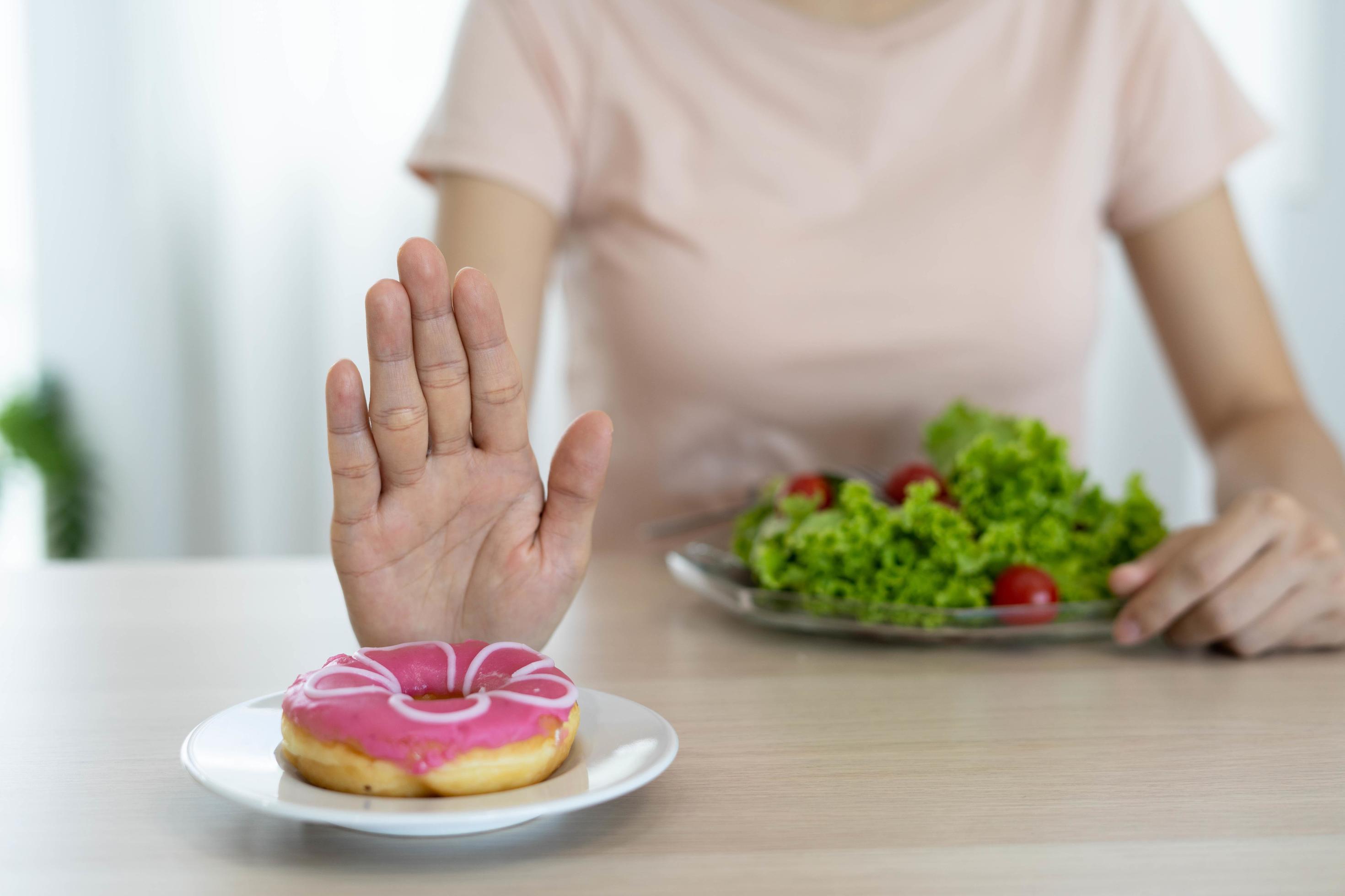 Good health food and diet. Women reject junk food or unhealthy foods such as doughnuts and choose healthy foods such as green apple. Stock Free