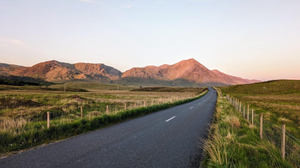 Empty scenic road trough nature and mountains at sunset, Inagh valley, Connemara, Galway, Ireland, landscape background, wallpaper Stock Free