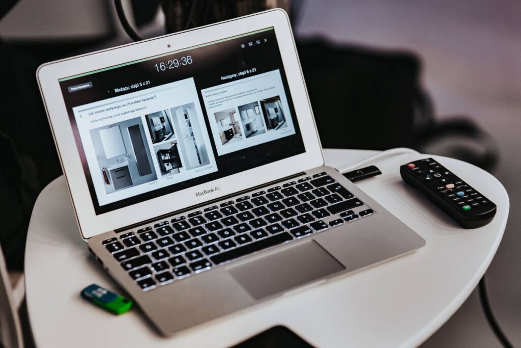 White laptop on a table with a remote Stock Free