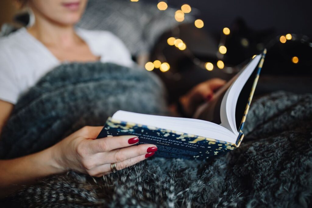 Young woman at home reading Hygge book and drinking Stock Free