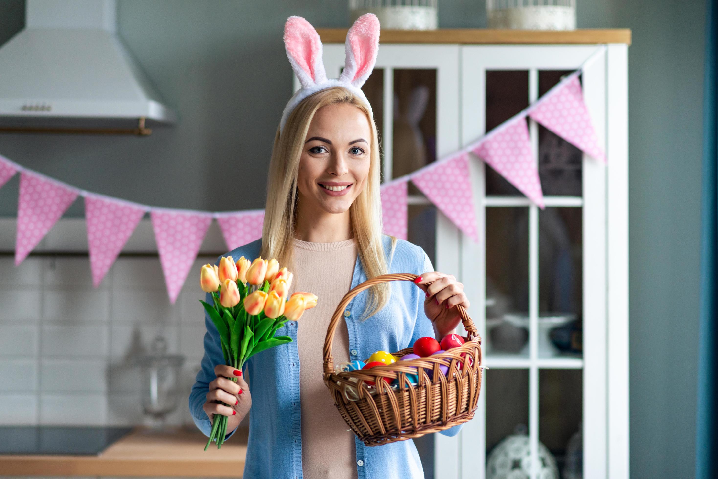 Beautiful blond woman holding flowers and Easter basket. Stock Free