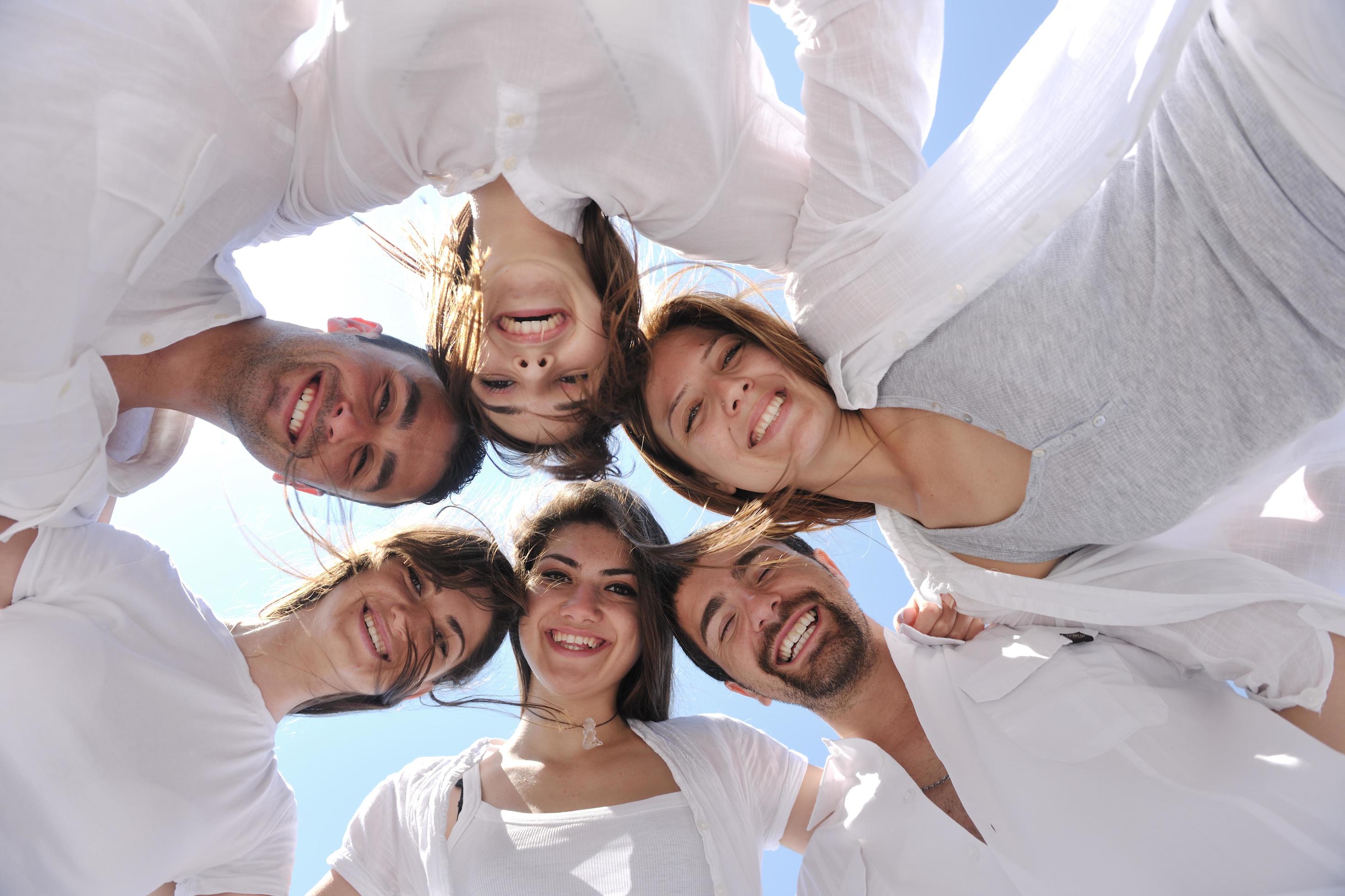 Group of happy young people in circle at beach Stock Free