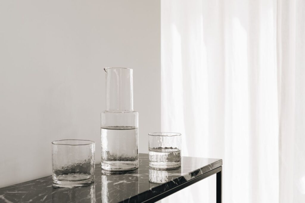 Water in a transparent glass carafe and glasses on a black marble console Stock Free