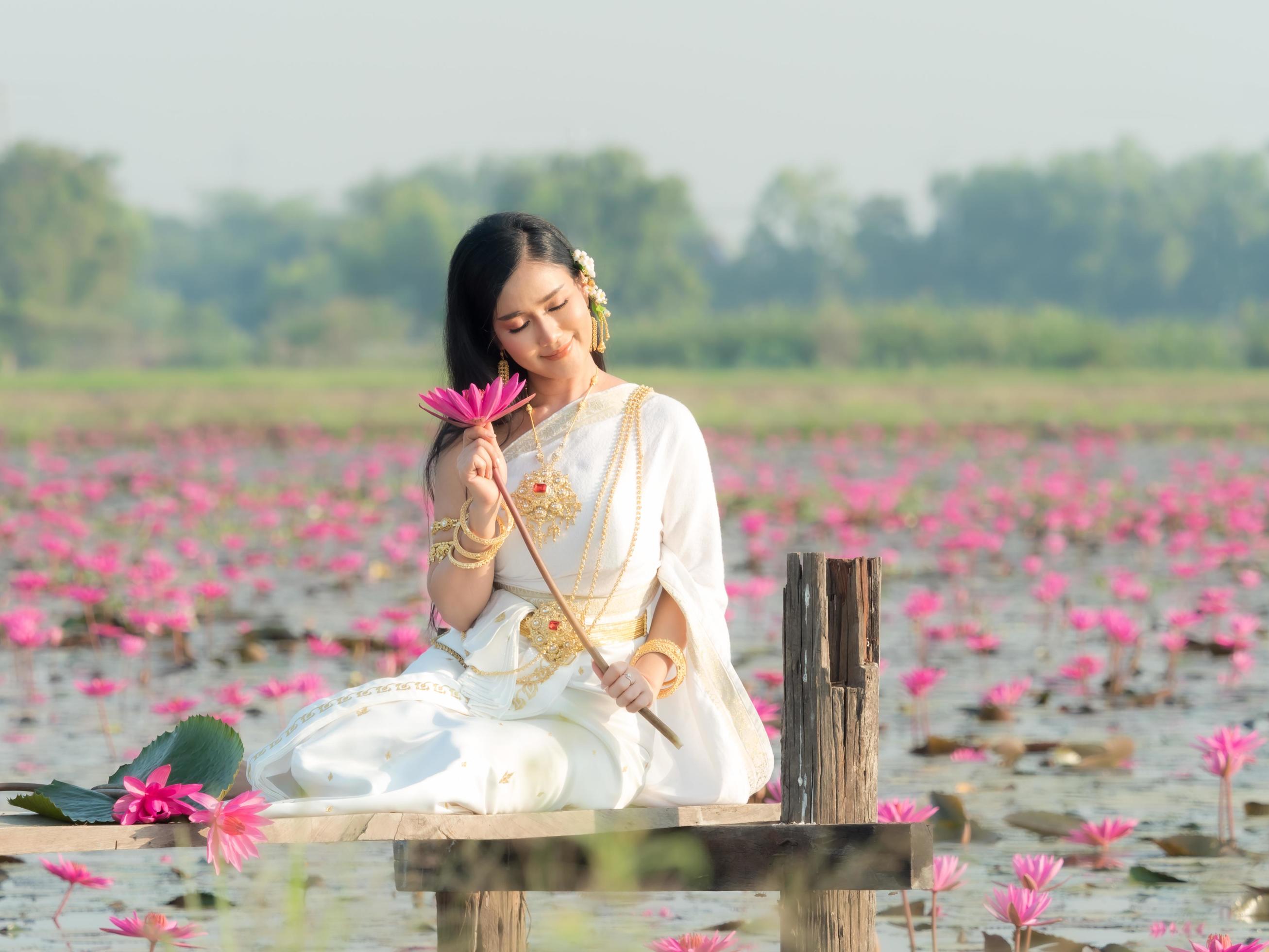 An elegant Thai woman wearing traditional Thai clothes carrying lotus flowers leaf collected from a lotus field Stock Free