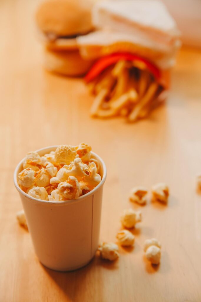 A bucket of popcorn, top-view, warm colors, light brown wooden background, flat lay, daylight macro close-up Stock Free