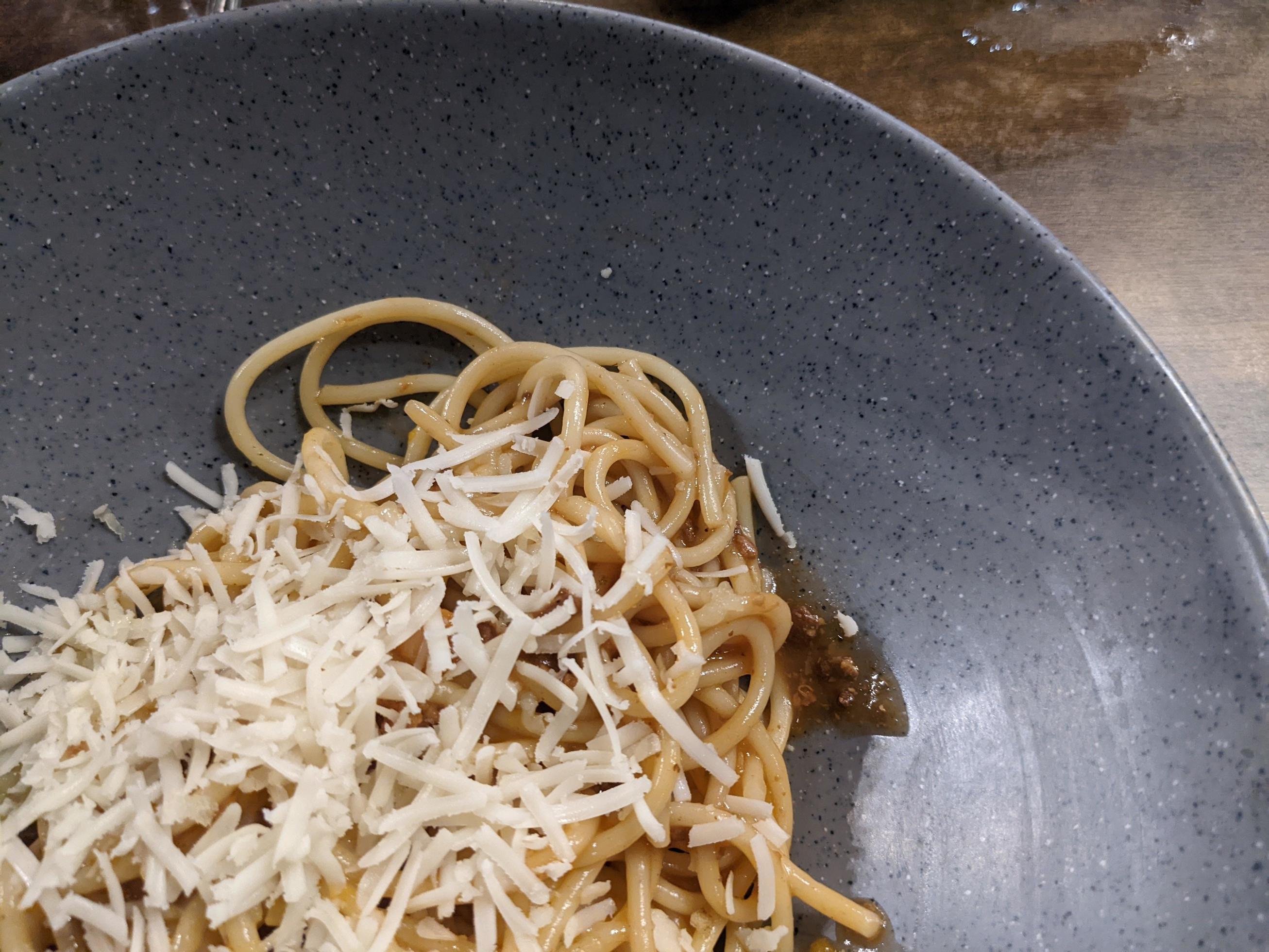 Spaghettis Bolognese with cheese cheddar topping on the grey bowl. The photo is suitable to use for food background, poster and food content. Stock Free