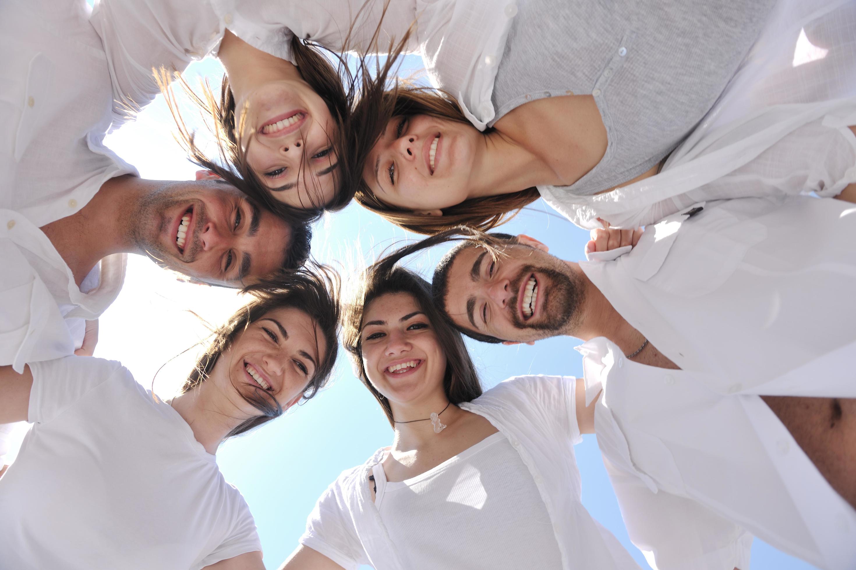 Group of happy young people in circle at beach Stock Free