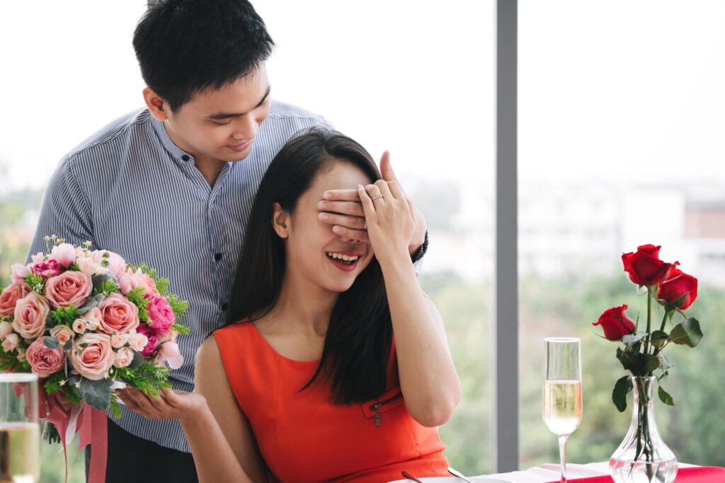 Lover with surpise flower bouquet at dinner table. Stock Free