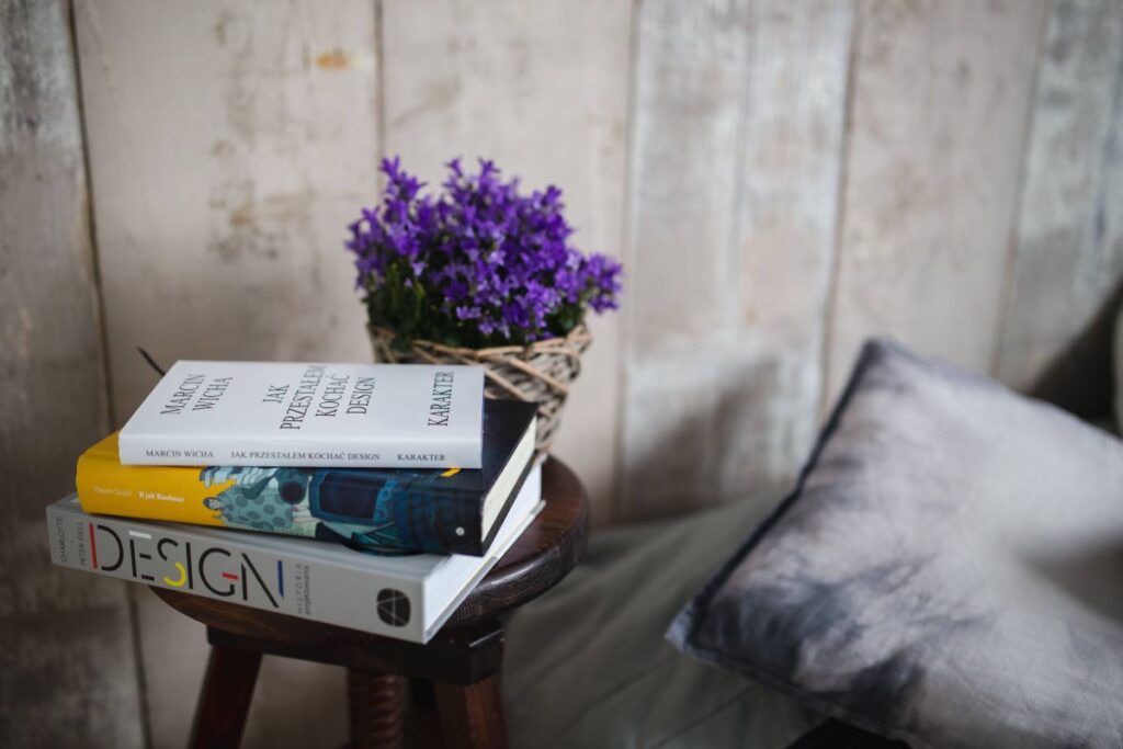 Books and purple flowers on a wooden stool by the bed Stock Free