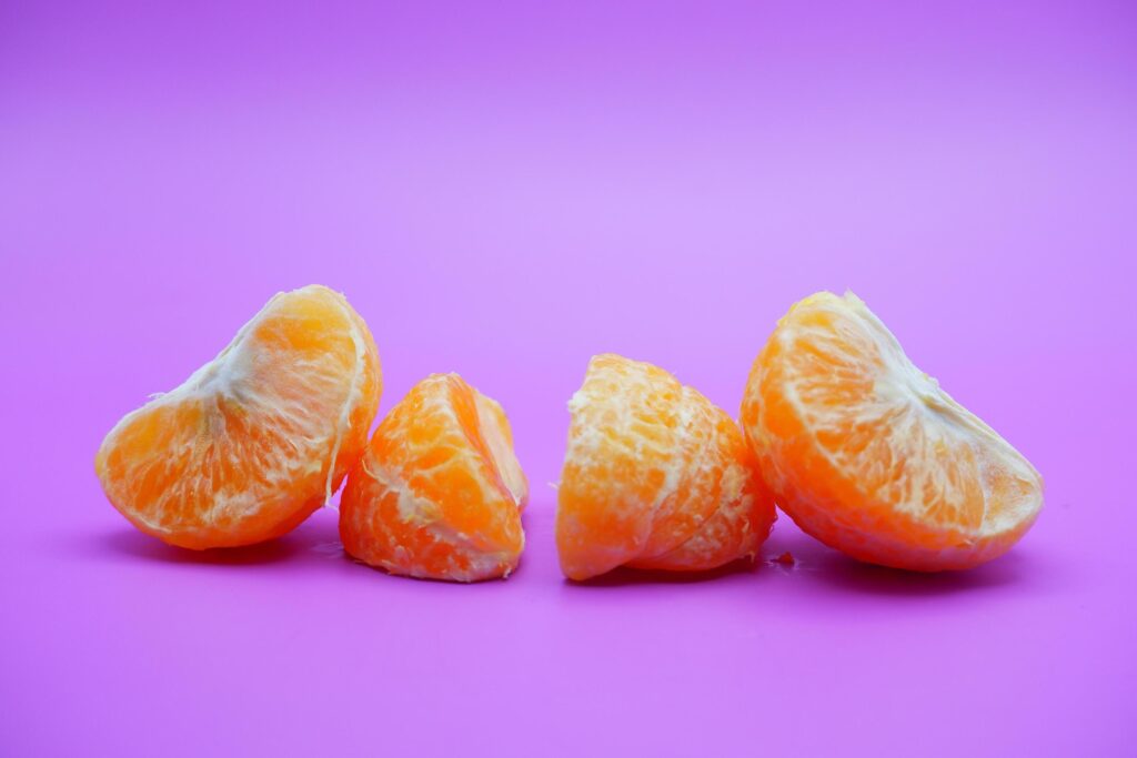 oranges that have been peeled and divided into several parts. orange isolated on purple background Stock Free